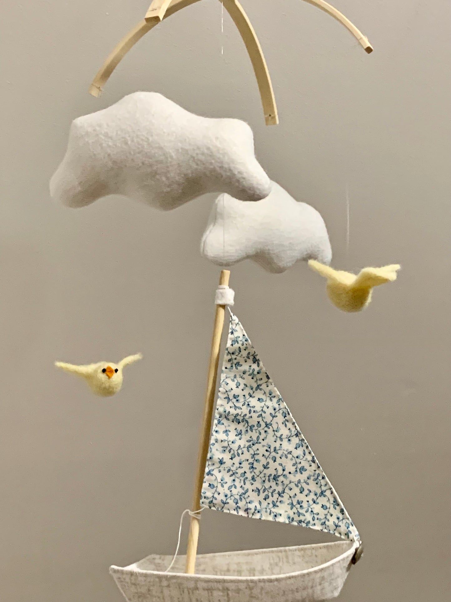 Decorative mobile with cloud, sailboat, and birds against a beige background