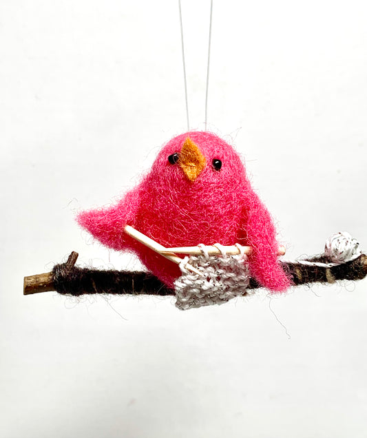 Pink bird ornament on a branch with a white background