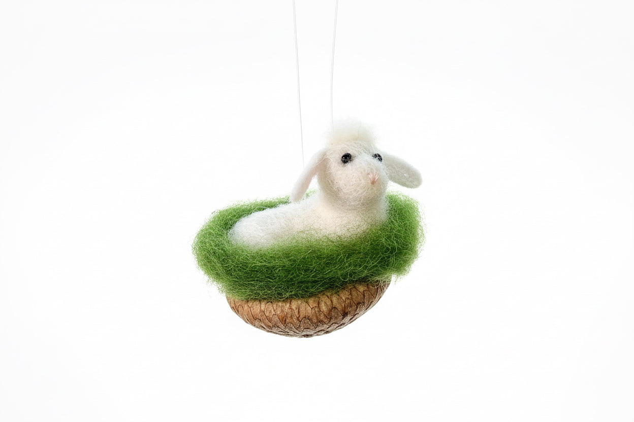 White sheep figurine on a green grassy base with a brown basket against a white background