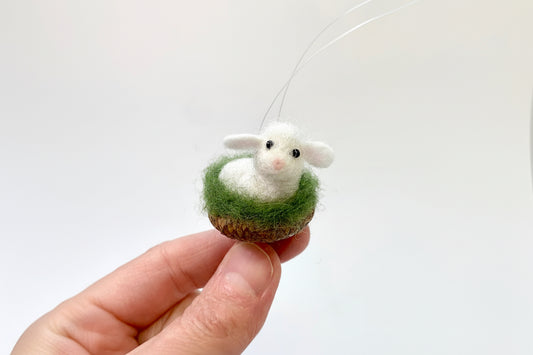 white needle felted little lamb nestled in an acorn cap ornament