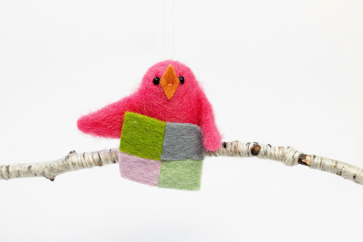 Felted bird toy with a colorful body on a branch against a white background